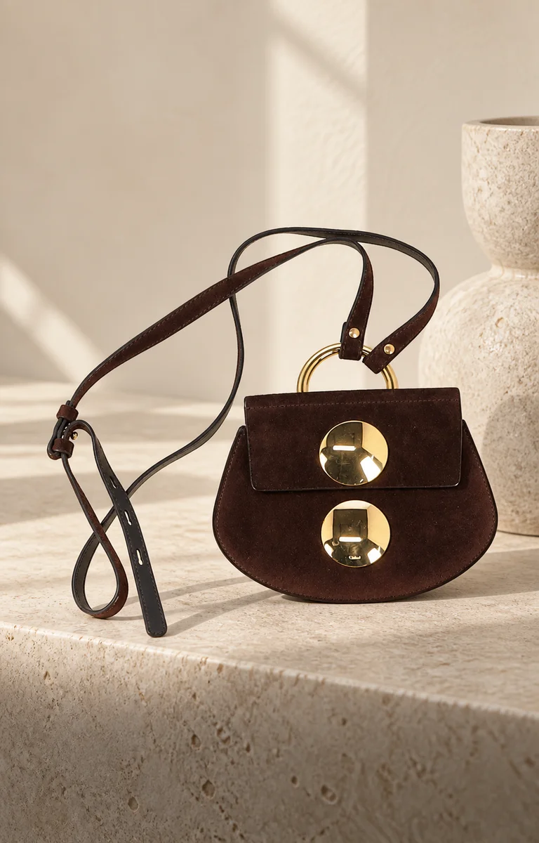 Brown shoulder bag on a warm stone plinth