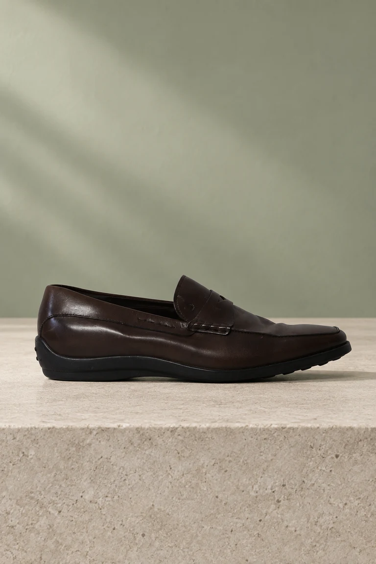 Unser brauner Pennyloafer aus Leder auf einem Steinsockel